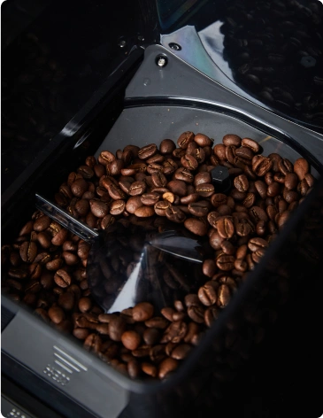 Contenedor con granos de café tostados en un molino