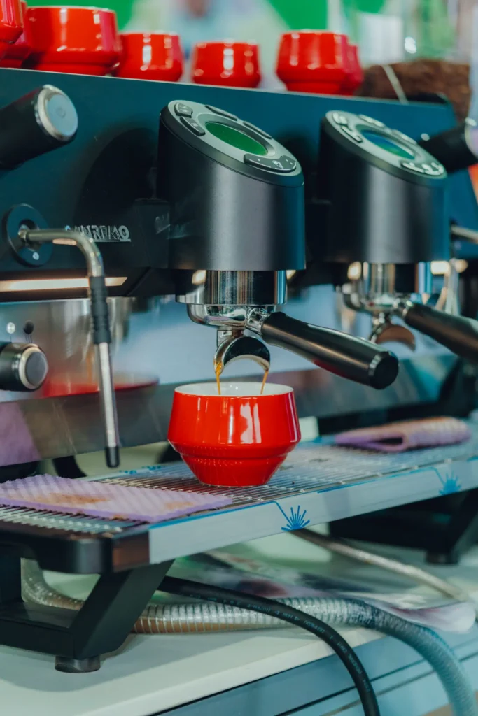 Cafetera espresso extrayendo café en una taza roja