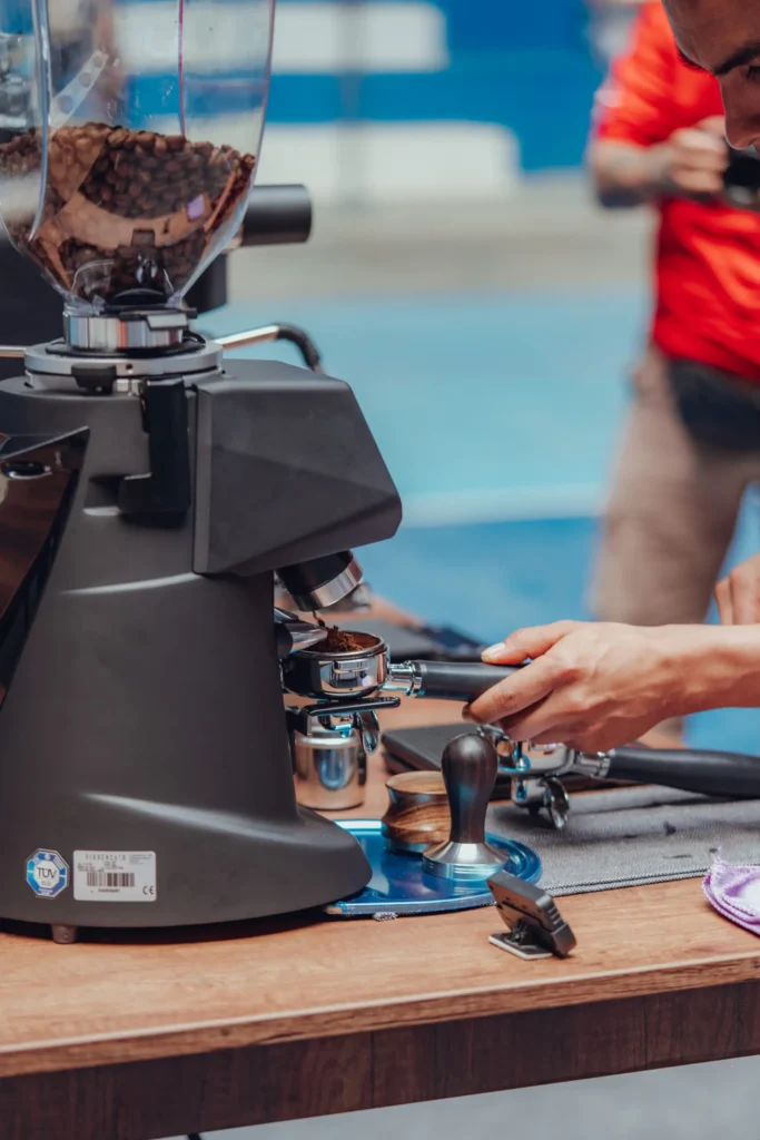Una persona utilizando un molino de café profesional para preparar café